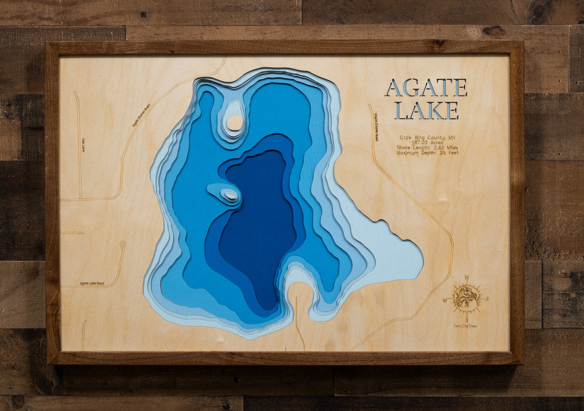 A laser-cut, layered wooden map of Agate Lake in Crow Wing County, Minnesota. The distinct shape of this natural lake, with its 2.63-mile shoreline, is clearly visible within the forested landscape of central Minnesota. The varying depths of the lake, reaching a maximum of 25 feet, are represented by different layers of wood, illustrating its impressive underwater topography.