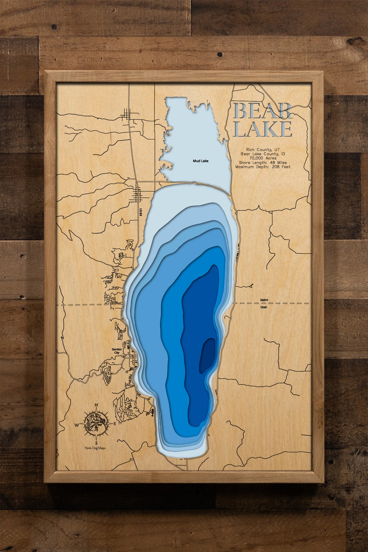 A beautifully crafted, laser-cut wooden topographic map of Bear Lake spanning the Utah-Idaho border across Rich and Bear Lake Counties, illustrating the lake's impressive 70,000-acre natural basin with depth contours showing the remarkable 208-foot maximum depth, the 48-mile shoreline featuring pristine white sand beaches, major landmarks including Garden City, Rendezvous Beach, and the North Beach area, and the stunning turquoise waters that earned it the nickname "Caribbean of the Rockies."