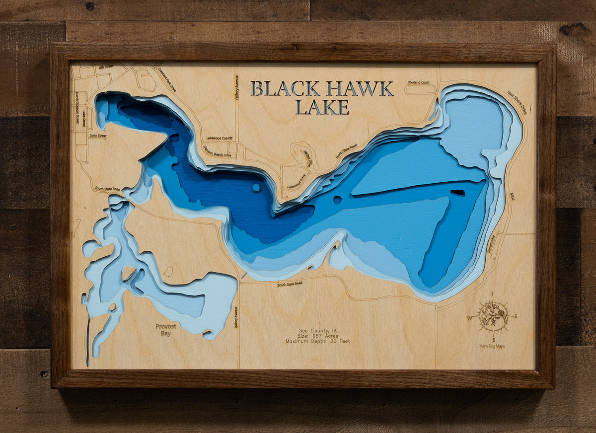A laser-cut, layered wooden map of Black Hawk Lake in Sac County, Iowa. The distinctive shape of the lake's shoreline is clearly visible, set within the surrounding landscape of Sac County. The varying depths of the lake are represented by different layers of wood, creating a three-dimensional effect.