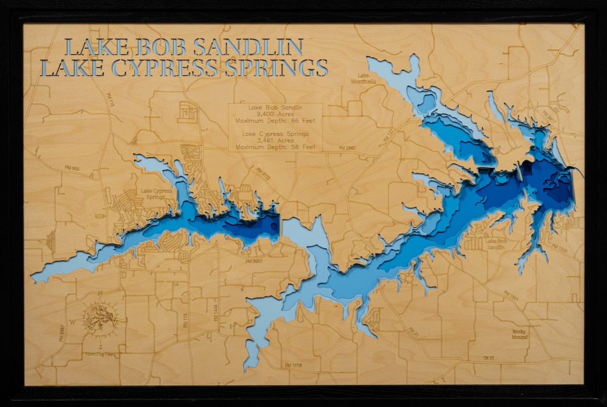 A framed topographical map art piece of Lake Bob Sandlin and Lake Cypress Springs, featuring layered blue and light blue wood cutouts over a natural tan wood background with engraved details and text.