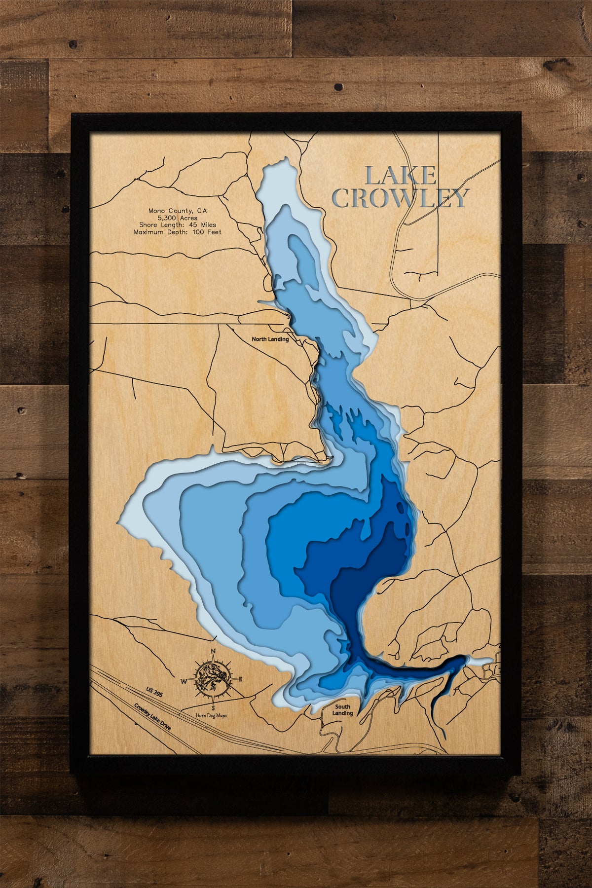 A precision laser-cut, multi-layered wooden map of Crowley Lake in Mono County, California — a legendary Eastern Sierra reservoir at 6,781 feet elevation. The natural wood top layer captures 45 miles of rugged High Desert shoreline in striking detail, while a light-to-dark blue gradient conveys the lake's 100-foot depth. A handcrafted statement piece for any California mountain cabin, fly fishing retreat, or Eastern Sierra enthusiast's wall.