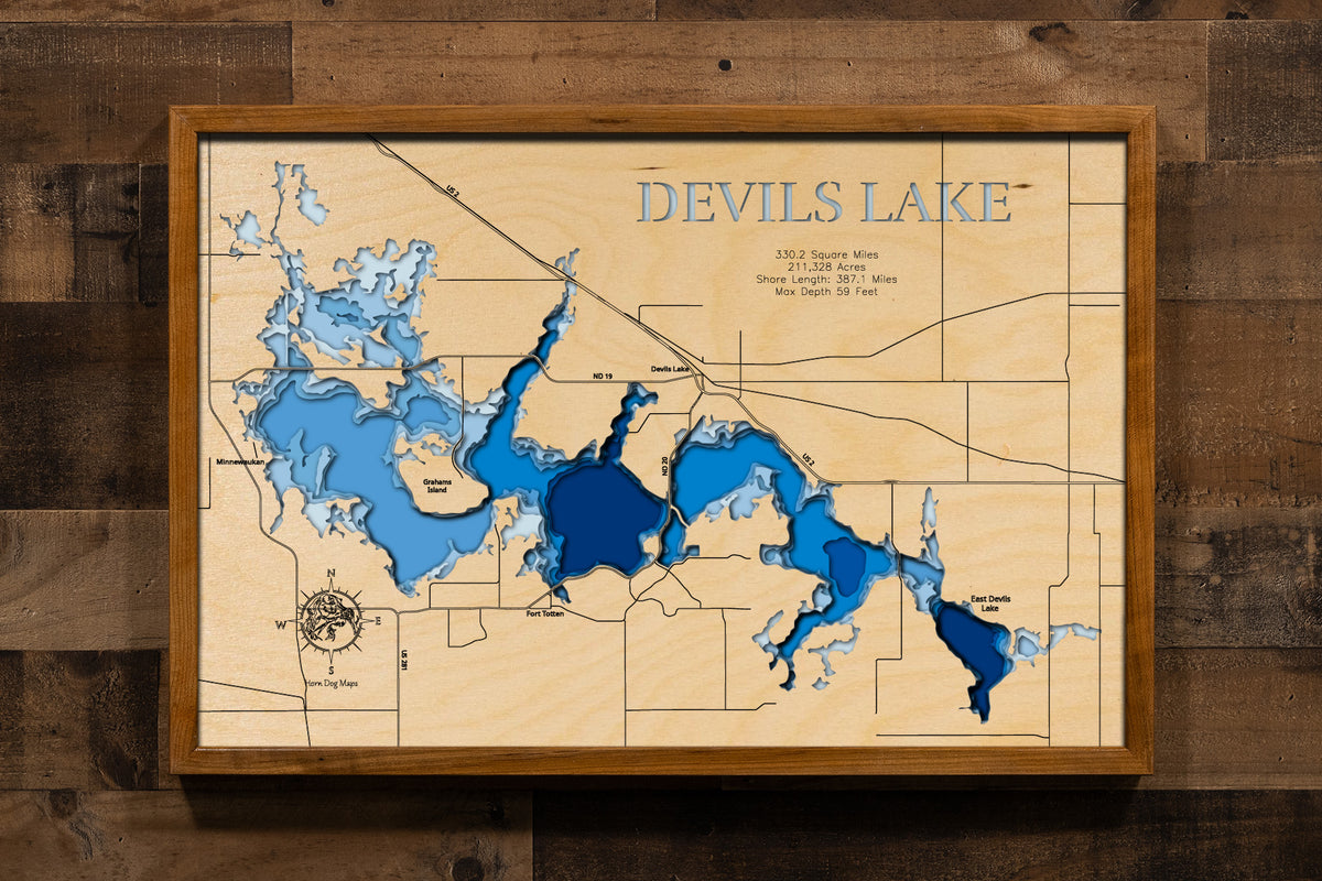 A highly detailed, 3D laser-cut wooden map of Devils Lake in Ramsey County, North Dakota. The multi-layered design uses different wood tones to illustrate the lake's bathymetric contours and deepest points. Etched details include the lake name, county lines, surrounding roads, and nearby landmarks, creating a unique and intricate piece of art.