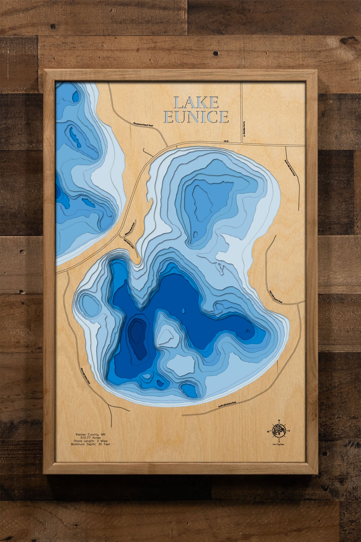 A precision laser-cut, multi-layered wooden map of Lake Eunice in Becker County, Minnesota, a 511-acre oligotrophic lake southwest of Detroit Lakes managed under experimental DNR fishing regulations for enhanced water quality and fishing. The natural wood top layer captures 3 miles of clear-water shoreline in fine detail, while a light-to-dark blue gradient conveys the lake's 30-foot depth. A handcrafted statement piece for any Minnesota lake home, cabin, or outdoor enthusiast's wall.