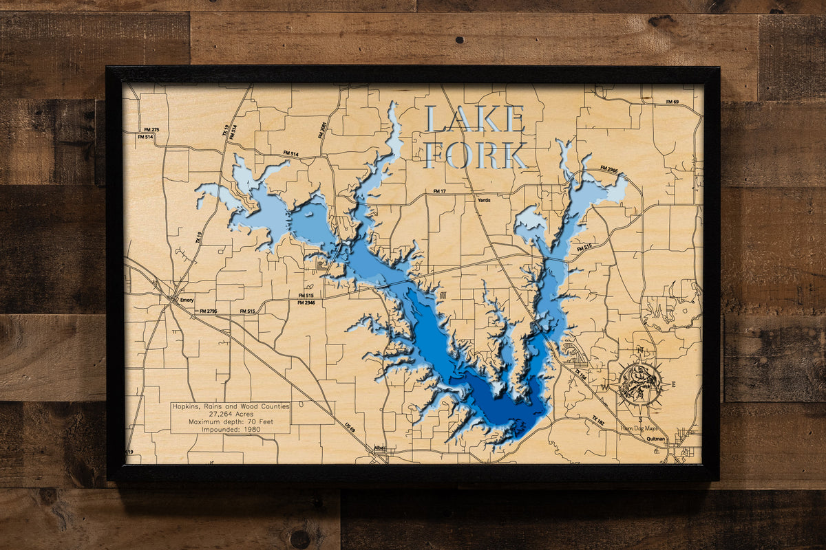 A highly detailed, 3D laser-cut wooden map of Lake Fork in Wood County, Texas. The multi-layered design uses different wood tones to illustrate the lake's bathymetric contours and deepest points. Etched details include the lake name, county lines, submerged timber, and surrounding roads, creating a unique and intricate piece of art.