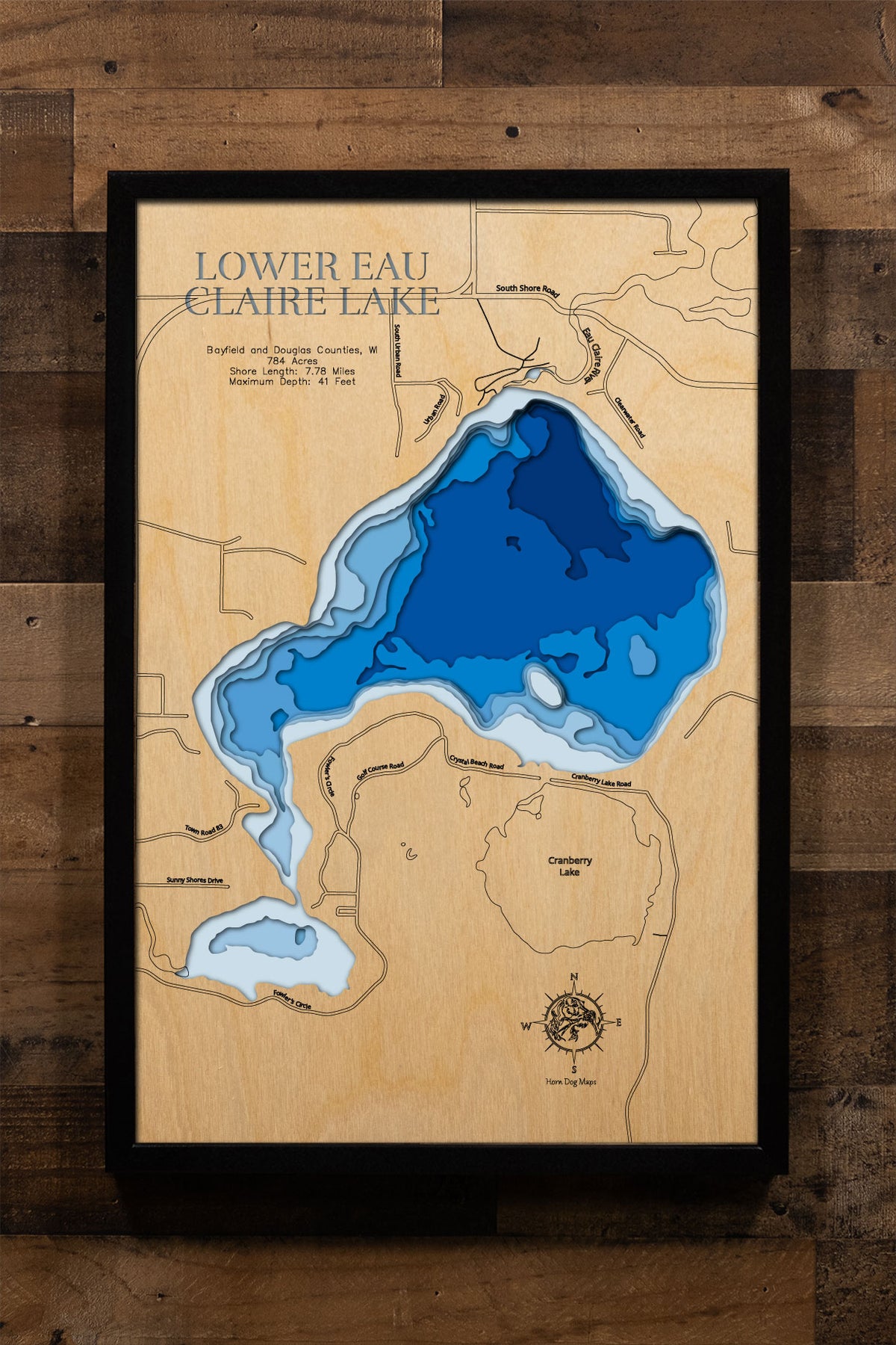 A precision laser-cut, multi-layered wooden map of Lower Eau Claire Lake in Bayfield and Douglas Counties, Wisconsin, a 784-acre Chequamegon National Forest lake and the southernmost link in the 11-lake Eau Claire Chain near Barnes. The natural wood top layer captures 7.78 miles of sandy shoreline in fine detail, while a light-to-dark blue gradient conveys its 41-foot depth. A handcrafted statement piece for any Wisconsin Northwoods cabin, lake home, or outdoor enthusiast's wall.