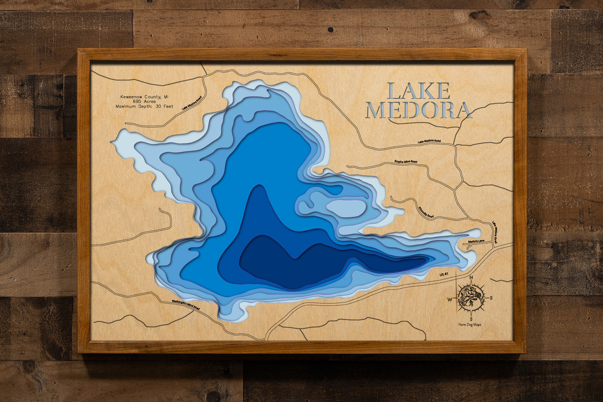 A meticulously detailed, laser-cut, multi-layered wooden map of Lake Medora in Keweenaw County, Michigan, showcasing the 695-acre wilderness lake with numerous scenic islands scattered throughout. The topographic design features natural wood layers highlighting the Canadian-like landscape and graduated blue water layers illustrating depths to the 30-foot maximum.