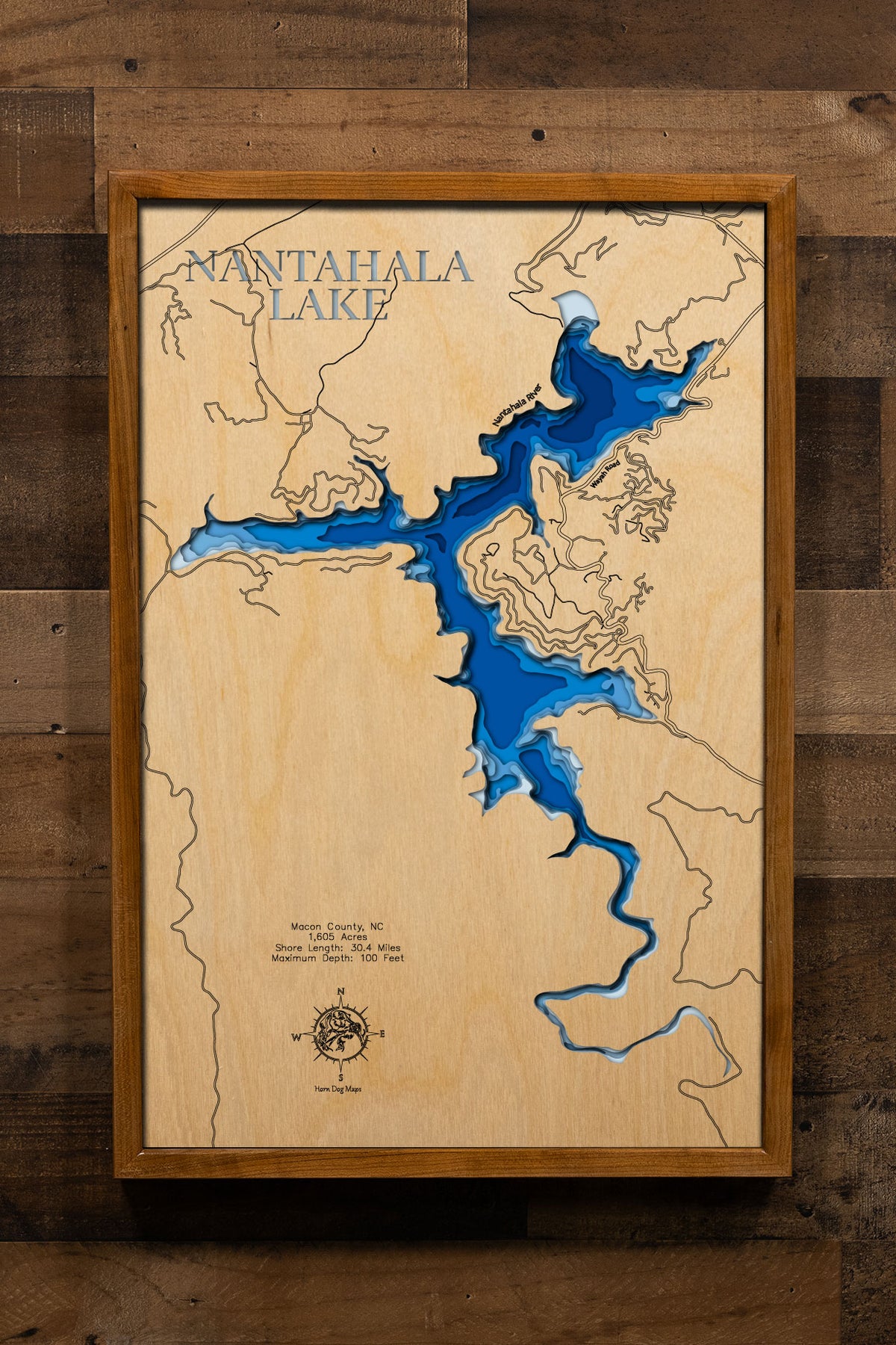 A precision laser-cut, multi-layered wooden map of Nantahala Lake in Macon County, North Carolina, a 1,605-acre high-elevation reservoir at 3,012 feet in the Nantahala National Forest with 30 miles of mountain shoreline and a maximum depth of 100 feet. The natural wood top layer captures every dramatic cove in fine detail, while a light-to-dark blue gradient conveys the lake's crystal-clear, cold-water depth. A handcrafted statement piece for any North Carolina mountain cabin or Appalachian retreat.