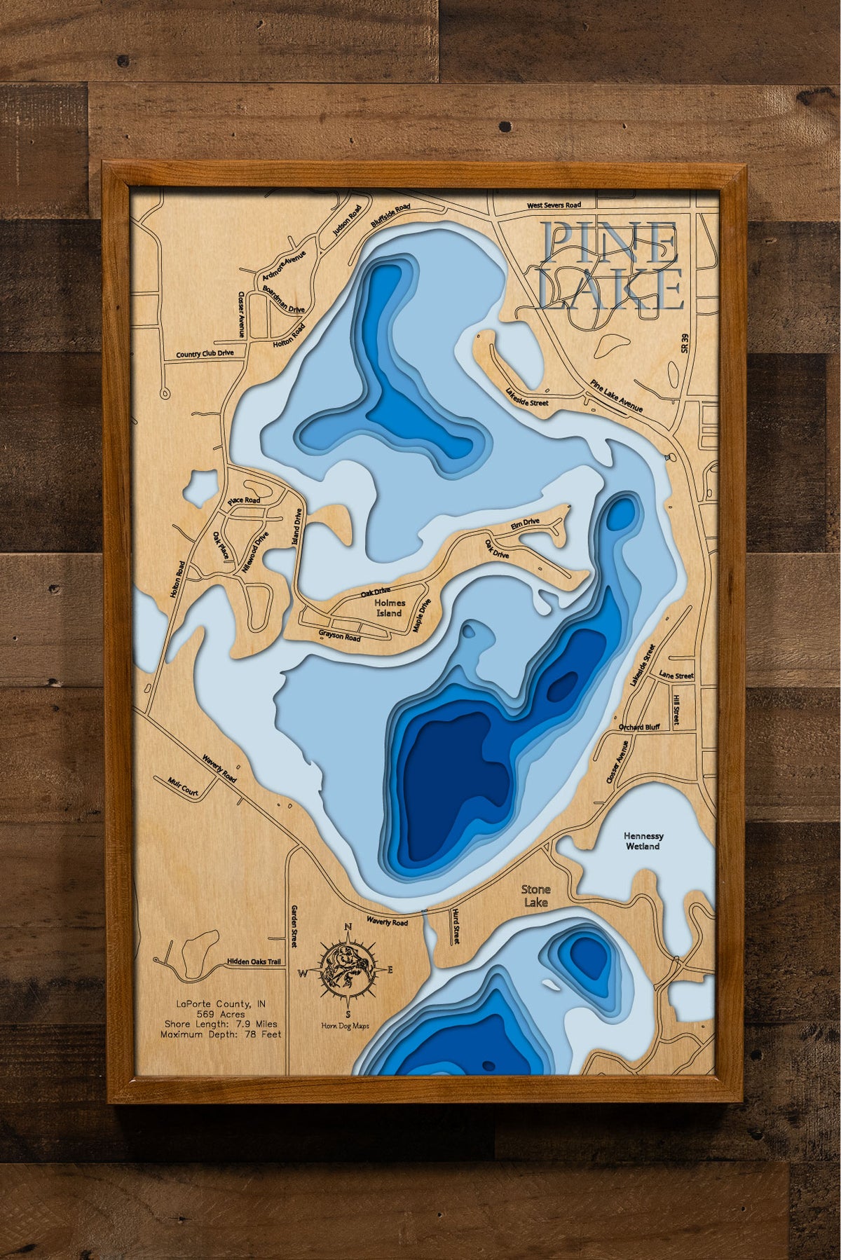 A highly detailed, laser-cut, and multi-layered wooden map of Pine Lake, a natural lake in LaPorte County, Indiana. The map shows the lake's distinct shape and its 7.9-mile shoreline. The varying depths of the lake, reaching a maximum of 78 feet, are represented by different layers of wood.