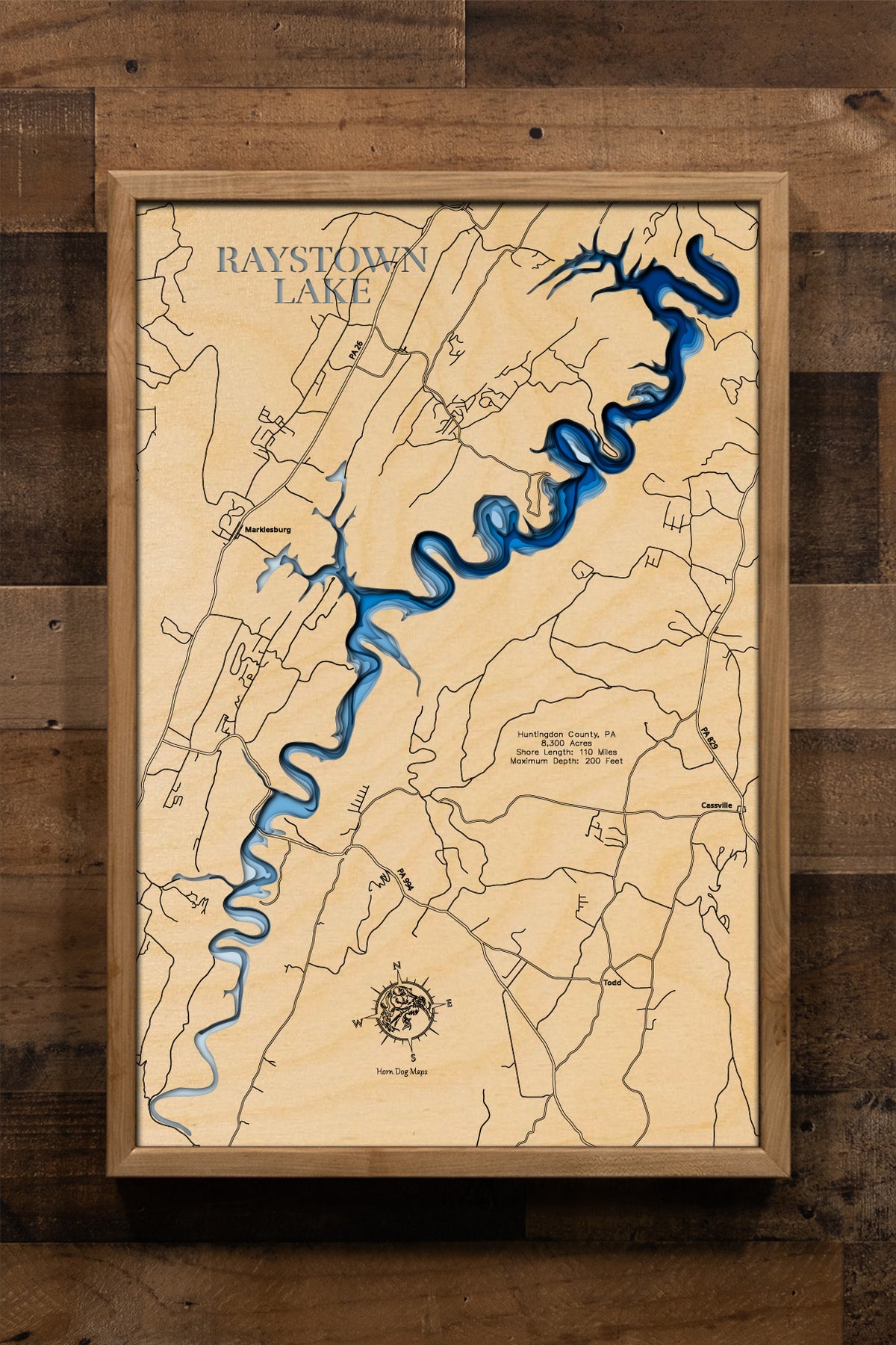 A highly detailed, laser-cut, and multi-layered wooden map of Raystown Lake, a large reservoir in Huntingdon County, Pennsylvania. The map shows the lake's distinct shape and its extensive 110-mile shoreline. The varying depths of the lake, reaching a maximum of 200 feet, are represented by different layers of wood.