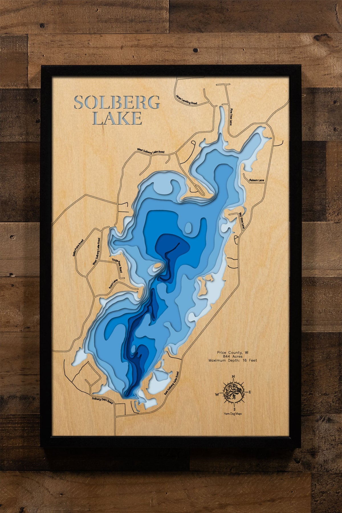A precision laser-cut, multi-layered wooden map of Solberg Lake in Price County, Wisconsin, an 844-acre impoundment north of Phillips featuring 11 islands and an irregular shoreline as part of the Phillips Chain of Lakes. The natural wood top layer captures every island and cove in fine detail, while a light-to-dark blue gradient conveys the lake's broad, shallow character. A handcrafted statement piece for any Wisconsin lake cabin, home, or outdoor enthusiast's wall.