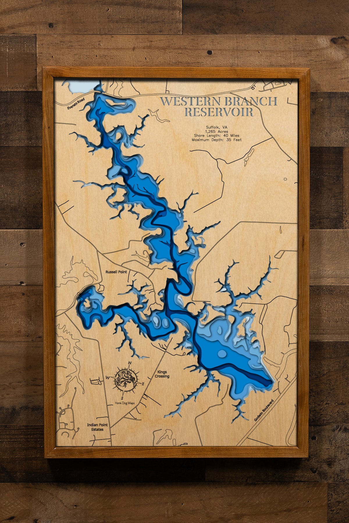 A magnificently detailed, laser-cut, multi-layered wooden topographical map of Western Branch Reservoir in Suffolk, Virginia, showcasing the 1,265-acre horseshoe-shaped water supply reservoir with 40 miles of irregular shoreline and connections to Lake Prince and Burnt Mills. The natural wood top layer frames two public boat launches, the dam on the western branch of Nansemond River, and sunken island hot spots, while graduated blue layers create a stunning visual gradient from shallow areas to the 35-foot