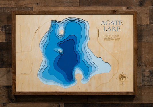 A laser-cut, layered wooden map of Agate Lake in Crow Wing County, Minnesota. The distinct shape of this natural lake, with its 2.63-mile shoreline, is clearly visible within the forested landscape of central Minnesota. The varying depths of the lake, reaching a maximum of 25 feet, are represented by different layers of wood, illustrating its impressive underwater topography.