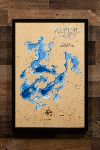 A meticulously detailed, laser-cut, multi-layered wooden topographical map of Alpine Lake in Cook County, Minnesota, showcasing the 909-acre wilderness lake within Superior National Forest with depth contours from moderate depths to the 65-foot maximum. The natural wood top layer frames approximately 10 miles of pristine shoreline near the Boundary Waters Canoe Area Wilderness, while graduated blue layers create a striking visual depth gradient.