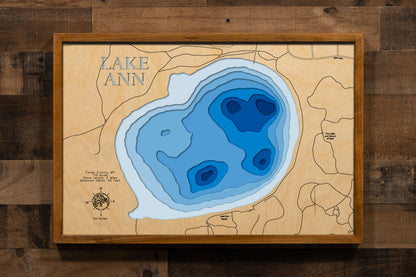 A precision laser-cut, multi-layered wooden map of Lake Ann in Carver County, Minnesota — a 119-acre deep, clear lake in Chanhassen that has met clean water standards for over 40 years. The natural wood top layer captures 2 miles of intimate shoreline in fine detail, while a light-to-dark blue gradient conveys the lake's 40-foot depth. A handcrafted statement piece for any Minnesota lake home, Twin Cities cabin, or outdoor enthusiast's wall.