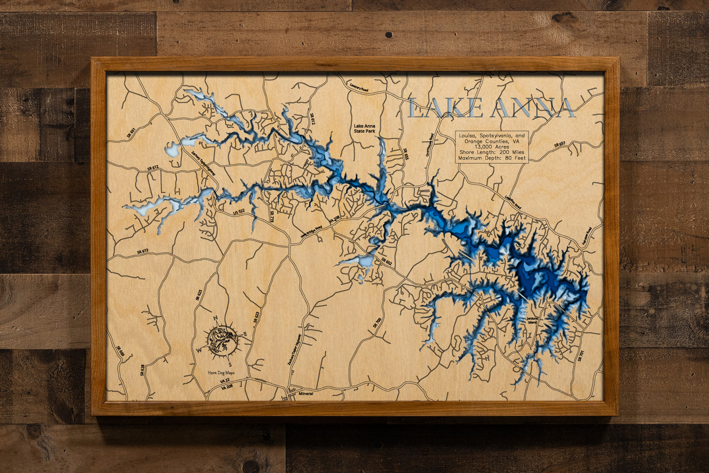 A magnificently detailed, laser-cut, multi-layered wooden topographical map of Lake Anna in Louisa, Spotsylvania, and Orange Counties, Virginia, showcasing the expansive 13,000-acre reservoir stretching 17 miles with an intricate 200 miles of shoreline. The natural wood top layer frames the three stone dikes dividing the public and private sides, the North Anna Dam, and countless coves and bays, while graduated blue layers create a stunning visual gradient from the 12-15-foot average depth to the 80-foot ma