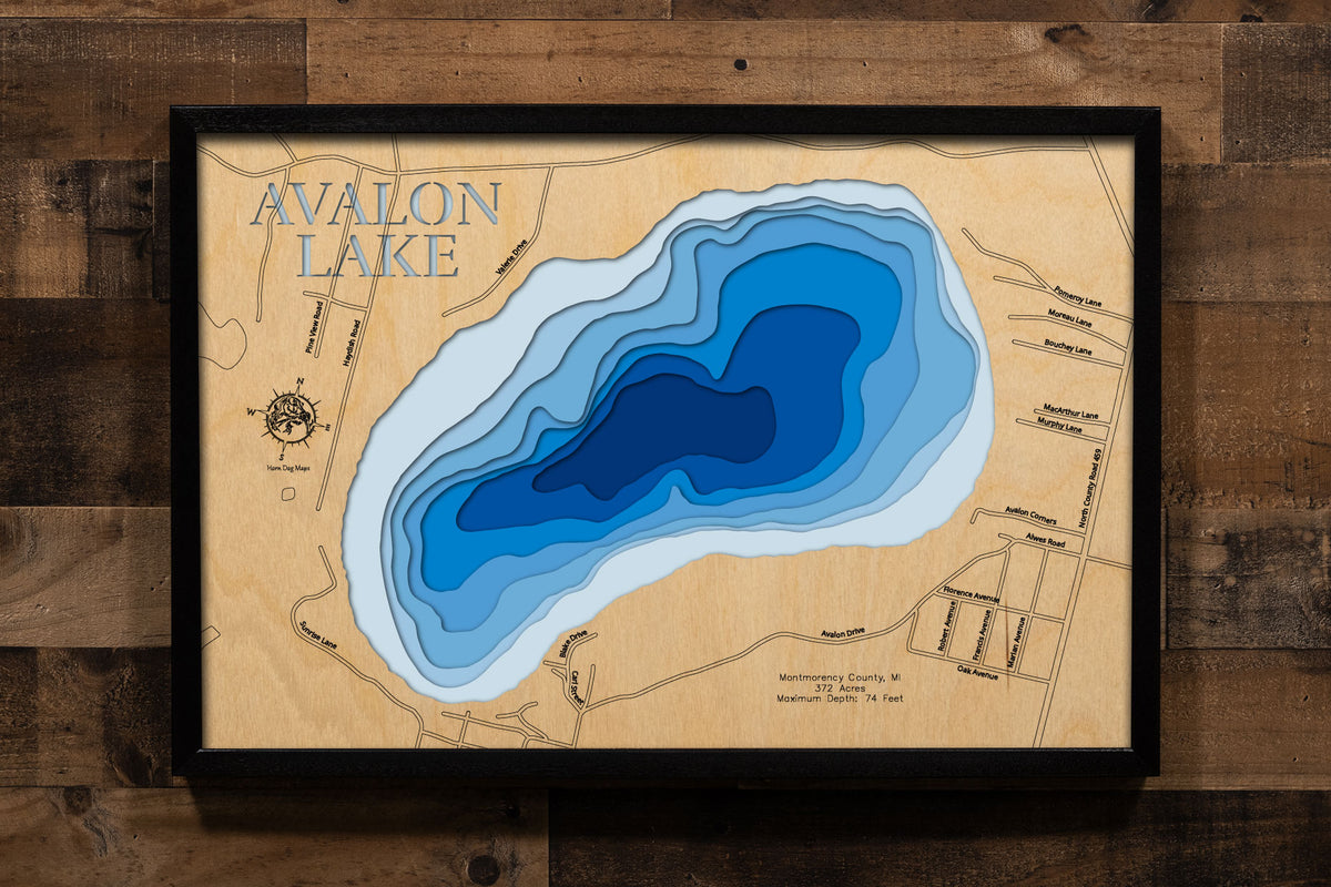 A precision laser-cut, multi-layered wooden map of Avalon Lake in Montmorency County, Michigan, a 372-acre cold-water seepage lake near Hillman renowned for its Splake fishery and 74-foot maximum depth. The natural wood top layer captures the lake's natural shoreline in fine detail, while a light-to-dark blue gradient conveys its striking depth and crystal-clear character. A handcrafted statement piece for any northern Michigan cabin, lake home, or outdoor enthusiast's wall.