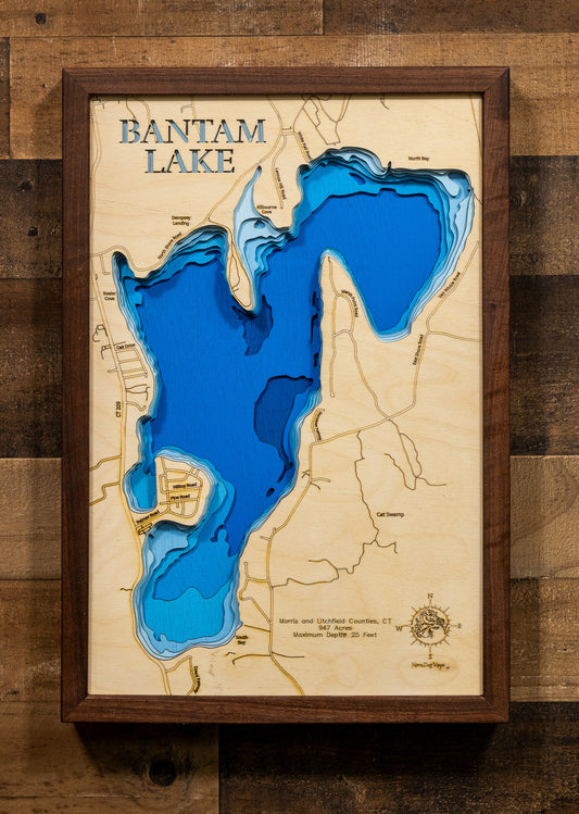 A laser-cut, layered wooden map of Bantam Lake, located in Morris and Litchfield Counties, Connecticut. The shape of Connecticut's largest natural lake is clearly defined within the northwestern Connecticut landscape. The varying depths of the lake, reaching a maximum of 25 feet, are represented by different layers of wood.