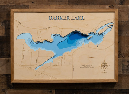 A laser-cut, layered wooden map of Barker Lake in Sawyer County, Wisconsin. The shape of the lake is visible within the northwestern Wisconsin landscape. The varying depths of the lake, reaching a maximum of 12 feet, are represented by different layers of wood.