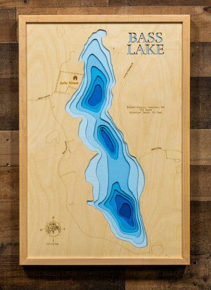 A detailed, laser-cut, multi-layered wooden map of Bass Lake in Becker County, Minnesota, showcasing the 123-acre lake near Snellman between Detroit Lakes and Park Rapids. The topographic design features natural wood layers highlighting the surrounding forest landscape and graduated blue water layers illustrating depths to the 50-foot maximum.
