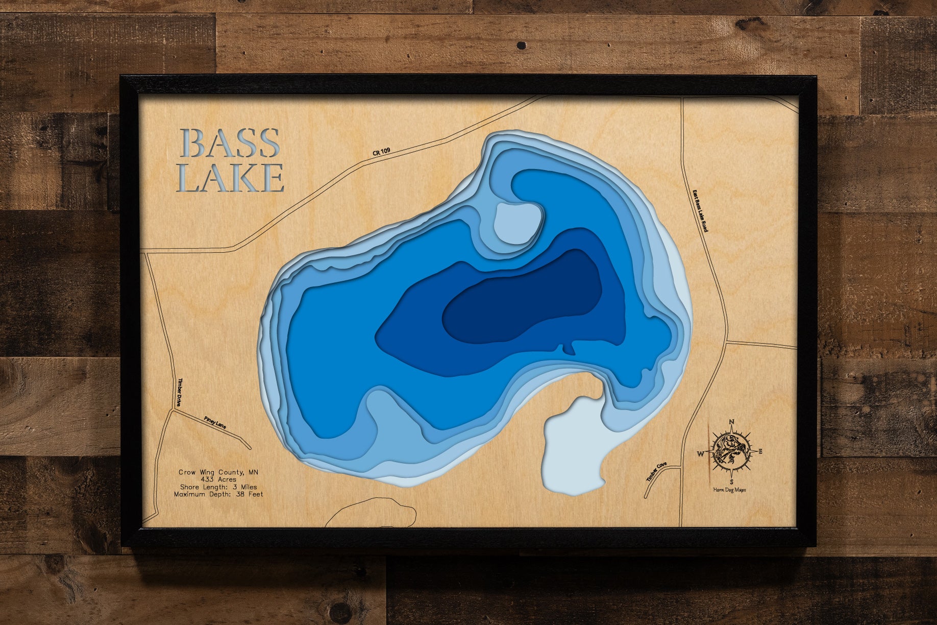 A precision laser-cut, multi-layered wooden map of Bass Lake in Crow Wing County, Minnesota, located near Merrifield in the heart of the Brainerd Lakes region. The natural wood top layer captures 3 miles of shoreline in fine detail, while a light-to-dark blue gradient conveys the lake's 38-foot depth. A handcrafted statement piece for any Minnesota lake cabin, home, or outdoor enthusiast's wall.