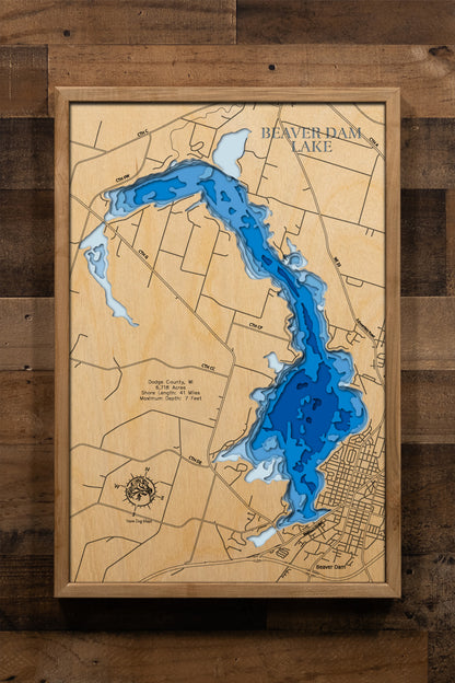 A precisely laser-cut, multi-layered wooden topographic map highlighting Beaver Dam Lake's remarkable 6,718-acre expanse across Dodge County, Wisconsin. The detailed relief map showcases the shallow bathymetry averaging 3 to 7 feet deep, the winding 41 miles of irregular shoreline bordered by the City of Beaver Dam and five surrounding townships, seven public boat launches, and the Beaver Dam River's flow through the impoundment.