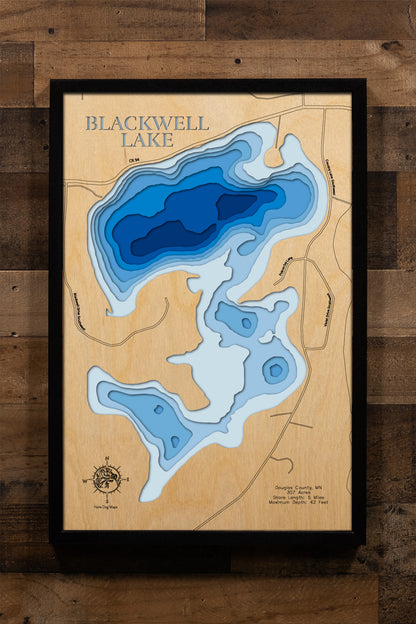 A meticulously detailed, laser-cut, multi-layered wooden topographical map of Blackwell Lake in Douglas County, Minnesota, showcasing the 307-acre lake's surface with depth contours from the 10-foot average depth to the 42-foot maximum. The natural wood top layer frames five miles of shoreline with the public boat launch and excellent 12.3-foot water clarity, while graduated blue layers create a striking visual depth gradient.