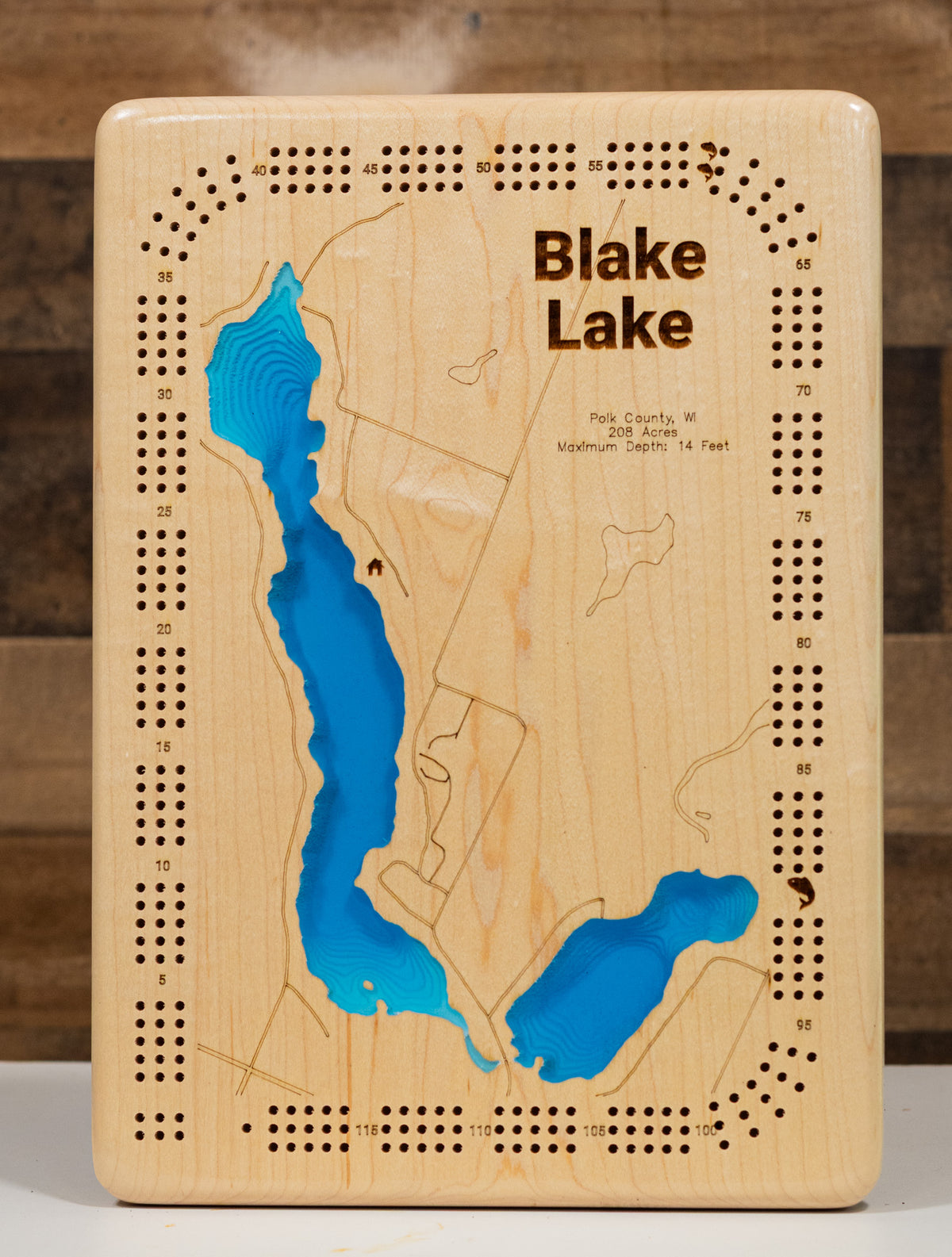 A precision laser-cut, multi-layered wooden map of Big Blake and Little Blake Lakes in Polk County, Wisconsin — a connected pair of Straight River drainage lakes covering 286 combined acres near Balsam Lake and Luck. The natural wood top layer captures both shorelines in fine detail, while a light-to-dark blue gradient conveys their warm, productive character. A handcrafted statement piece for any Wisconsin lake cabin, home, or outdoor enthusiast's wall.