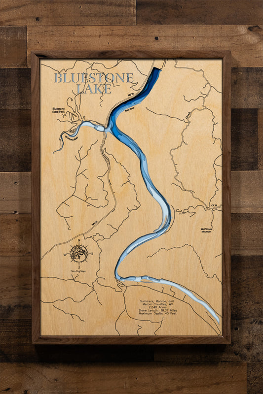 A precision laser-cut, multi-layered wooden map of Bluestone Lake spanning Summers, Monroe, and Mercer Counties, West Virginia. The natural wood top layer traces the lake's rugged, river-carved Appalachian shoreline in fine detail, while a light-to-dark blue gradient highlights the water's depth and dimension. A distinctive, rustic statement piece for any mountain cabin, lake home, or West Virginia outdoor enthusiast's space.