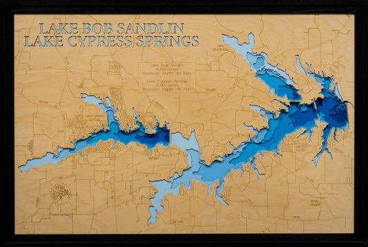 A framed topographical map art piece of Lake Bob Sandlin and Lake Cypress Springs, featuring layered blue and light blue wood cutouts over a natural tan wood background with engraved details and text.