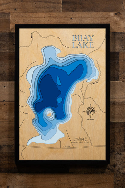 A highly detailed, laser-cut, and multi-layered wooden map of Bray Lake in Itasca County, Minnesota. The map showcases the lake's compact 177-acre surface with depth contours illustrating the descent to its impressive 44-foot maximum depth, the shallow vegetated southern bay with carry-in access, and the intimate 3 miles of forested shoreline.