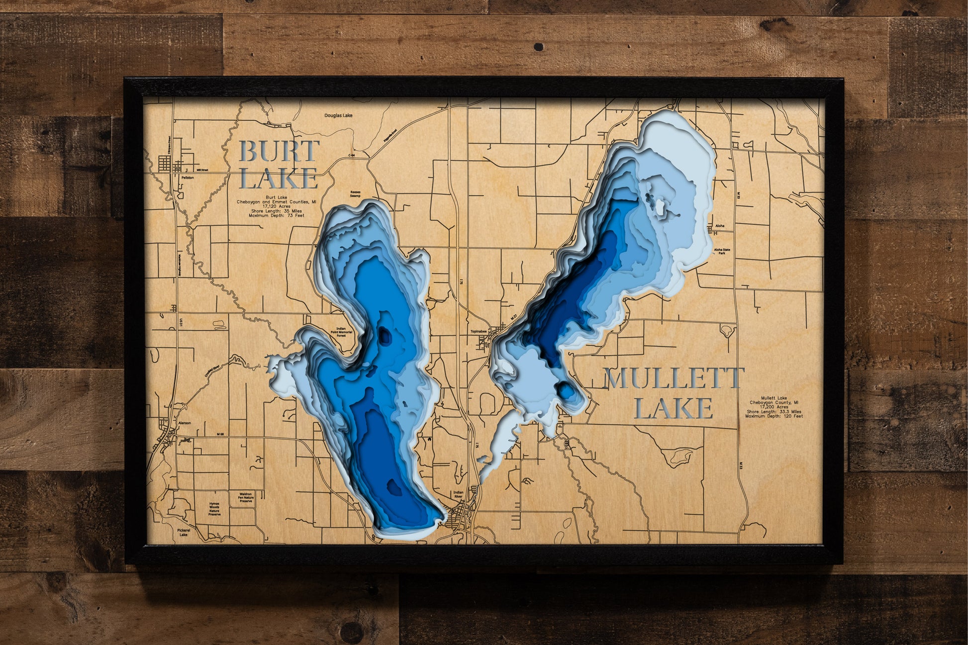 A highly detailed, laser-cut, and multi-layered wooden map showcasing both Burt Lake and Mullett Lake in Cheboygan County, Michigan. The map illustrates Burt Lake's 17,120-acre surface with depth contours to 73 feet and 35 miles of shoreline, alongside Mullett Lake's 17,360-acre expanse descending to 120 feet with 28 miles of shoreline, connected by the Indian River corridor through the famous Inland Waterway.