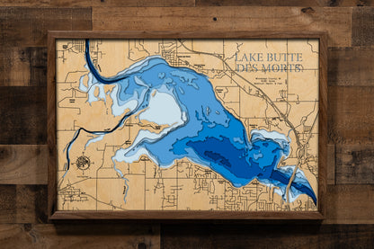 A detailed laser-cut wooden map of Lake Butte des Morts in Winnebago County, Wisconsin, highlighting its 8,581-acre surface and the flow of the Fox and Wolf Rivers. The 19-mile shoreline is precisely etched, showcasing the lake's connection to the Winnebago Pool system. Depth contours emphasize the shallow 9-foot basin, while local landmarks and Terrell’s Island are featured in the natural wood finish.