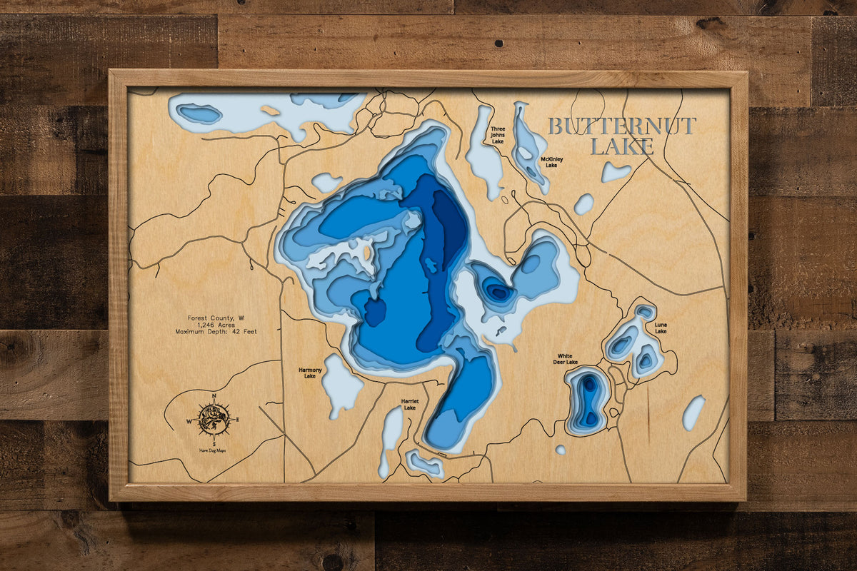 A precision laser-cut, multi-layered wooden map of Butternut Lake in Forest County, Wisconsin, a 1,246-acre spring-fed lake near Alvin in the Chequamegon-Nicolet National Forest renowned for its exceptional clarity and premier Walleye fishery. The natural wood top layer captures the lake's expansive shoreline in fine detail, while a light-to-dark blue gradient conveys its 42-foot depth and brilliant clear-water character.