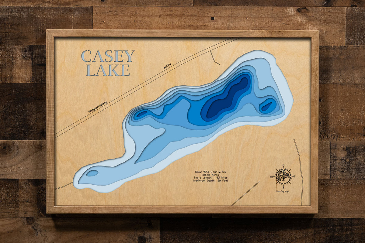A precision laser-cut, multi-layered wooden map of Casey Lake in Crow Wing County, Minnesota, a 59.58-acre Natural Environment lake near Cuyuna with a maximum depth of 39 feet. The natural wood top layer captures 1.63 miles of shoreline in fine detail, while a light-to-dark blue gradient conveys the lake's surprising depth. A handcrafted statement piece for any Minnesota lake cabin, home, or outdoor enthusiast's wall.