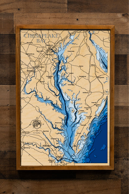 A laser-cut, layered wooden map of the Chesapeake Bay, located in Maryland, Virginia, and Delaware. The expansive and intricate shape of this major estuary, with its numerous tributaries and coastline, is clearly visible within the Mid-Atlantic landscape. The varying depths of the bay, reaching a maximum of 174 feet, are represented by different layers of wood, illustrating its underwater topography.