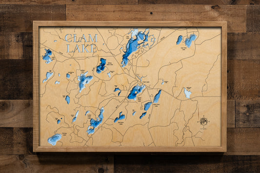A magnificently detailed, laser-cut, multi-layered wooden topographical map of the Clam Lake area lakes in Ashland and Sawyer Counties, Wisconsin, showcasing the interconnected chain of Upper Clam, Lower Clam, White Bass, Day, and surrounding lakes with intricate shorelines winding through the Chequamegon National Forest. The natural wood top layer frames the pristine wilderness character and elk habitat, while graduated blue layers create a stunning visual depth gradient across this premier northwoods fish
