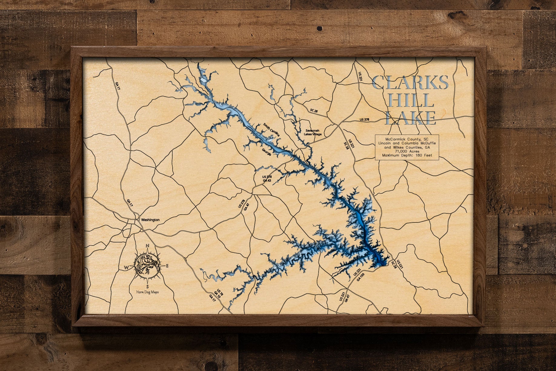 A laser-cut, layered wooden map of Clarks Hill Lake, located in Columbia, Elbert, Lincoln, and McDuffie Counties, Georgia. The expansive and intricate shape of the reservoir, stretching along the Savannah River, is clearly visible within the eastern Georgia landscape. The varying depths of the lake, reaching a maximum of 180 feet, are represented by different layers of wood, illustrating its underwater topography.