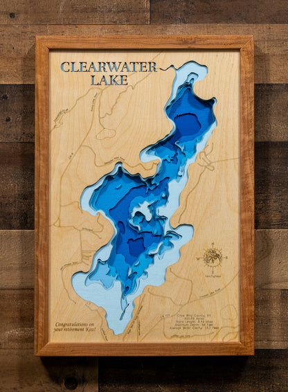 A framed 3D wooden map of Clearwater Lake, featuring layered blue and light blue wood sections representing the lake depths, mounted on a rustic dark wood plank wall.