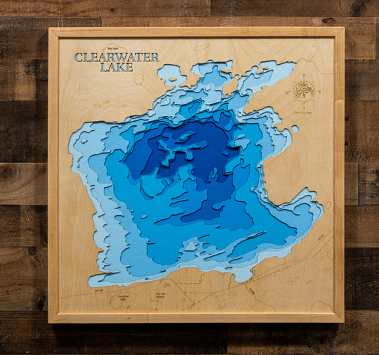 A square wooden depth map plaque of Clearwater Lake, featuring layered blue and light blue wood sections representing the lake's contours, mounted on a dark wood plank background.