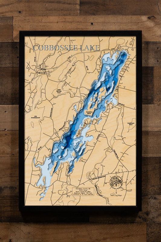 A laser-cut, layered wood map of Cobbosseecontee Lake, Kennebec County, Maine, showing its winding shoreline, wooded perimeter, and clustered islands.