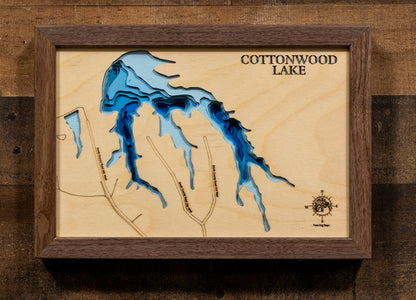 A meticulously crafted laser-cut wooden map of Cottonwood Lake in 
Greensburg, Indiana. This 3D topographic piece features a natural 
wood top layer representing the land, with recessed water layers 
stained in a light-to-dark blue gradient to reflect the lake's 
65-foot depth. It is a striking decor item that highlights the 
intricate details of the 30-acre reservoir and its 1.2-mile 
shoreline, ideal for any modern or rustic interior.