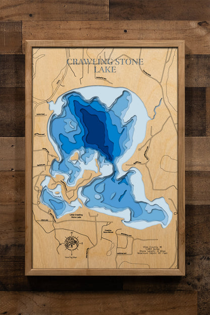 A magnificently detailed, laser-cut, multi-layered wooden topographical map of Crawling Stone Lake in Vilas County, Wisconsin, showcasing the 1,483-acre pristine lake on the Fence Chain with exceptional 15-foot water clarity and intricate depth contours from sandy beaches to the 87-foot maximum depth. The natural wood top layer frames nine miles of shoreline including islands and the connection to Little Crawling Stone Lake, while graduated blue layers create a stunning visual depth gradient.