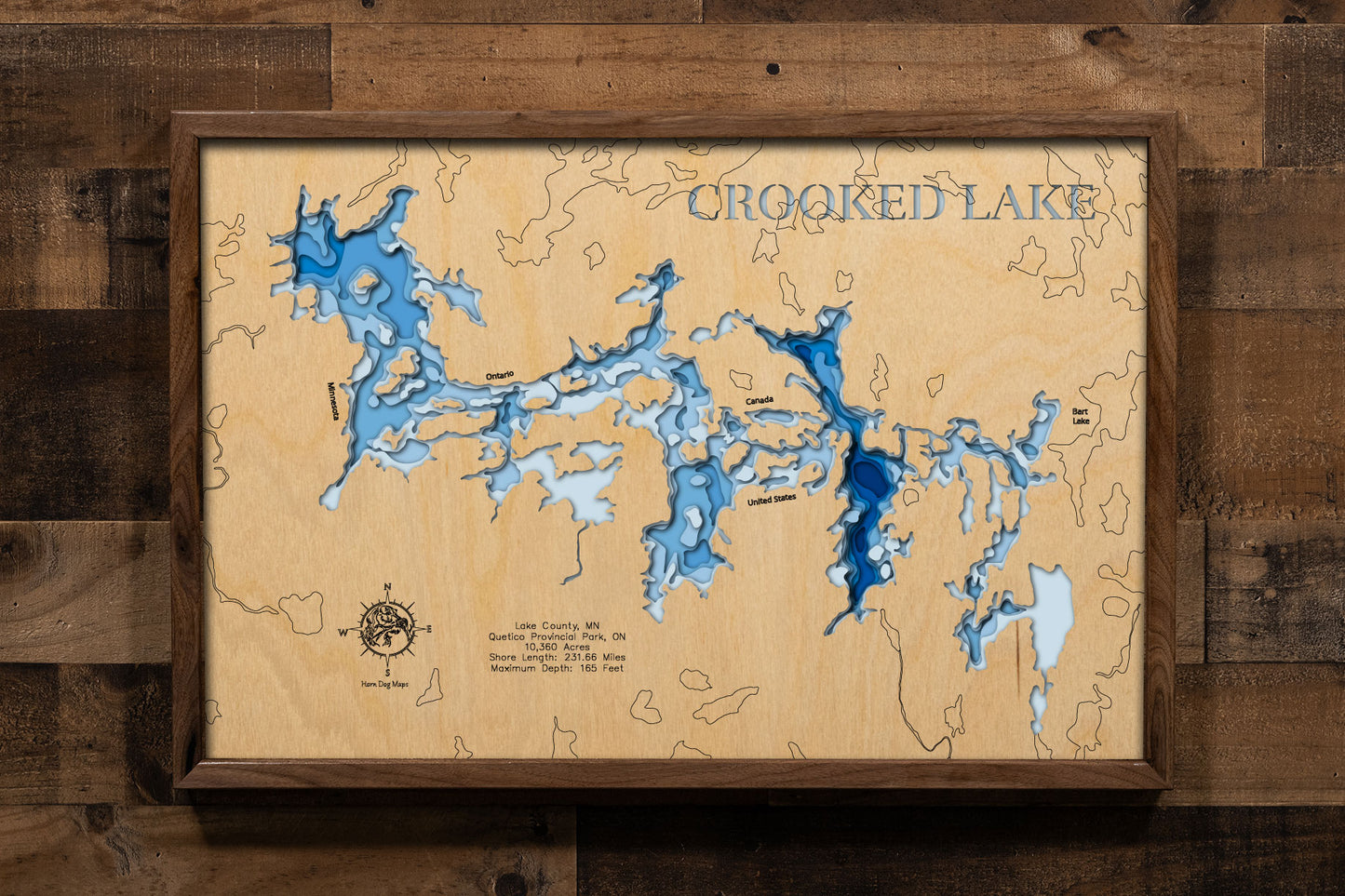 A precision laser-cut, multi-layered wooden map of Crooked Lake on the Minnesota-Ontario border, a 10,360-acre BWCA and Quetico wilderness lake with 231 miles of serpentine shoreline and a maximum depth of 165 feet. The natural wood top layer captures every dramatic bay and island in fine detail, while a light-to-dark blue gradient conveys the lake's striking depth. A handcrafted statement piece for any BWCA paddler's cabin, Northwoods home, or wilderness enthusiast's wall.