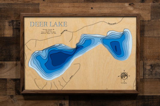 A highly detailed, laser-cut, and multi-layered wooden map of Deer Lake in Burnett County, Wisconsin. The map showcases the lake's compact 153-acre surface with shallow depth contours reaching a maximum of 23 feet, the predominantly sandy bottom composition, and 2.5 miles of undeveloped shoreline surrounded by pristine county forest lands.