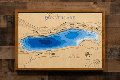A precision laser-cut, multi-layered wooden map of Donner Lake in Nevada County, California — a storied Sierra Nevada alpine lake near Truckee at 5,936 feet elevation. The natural wood top layer captures 8 miles of pine-lined mountain shoreline in fine detail, while a light-to-dark blue gradient conveys the lake's striking 238-foot depth. A handcrafted statement piece for any California mountain cabin, Sierra Nevada retreat, or outdoor enthusiast's wall.