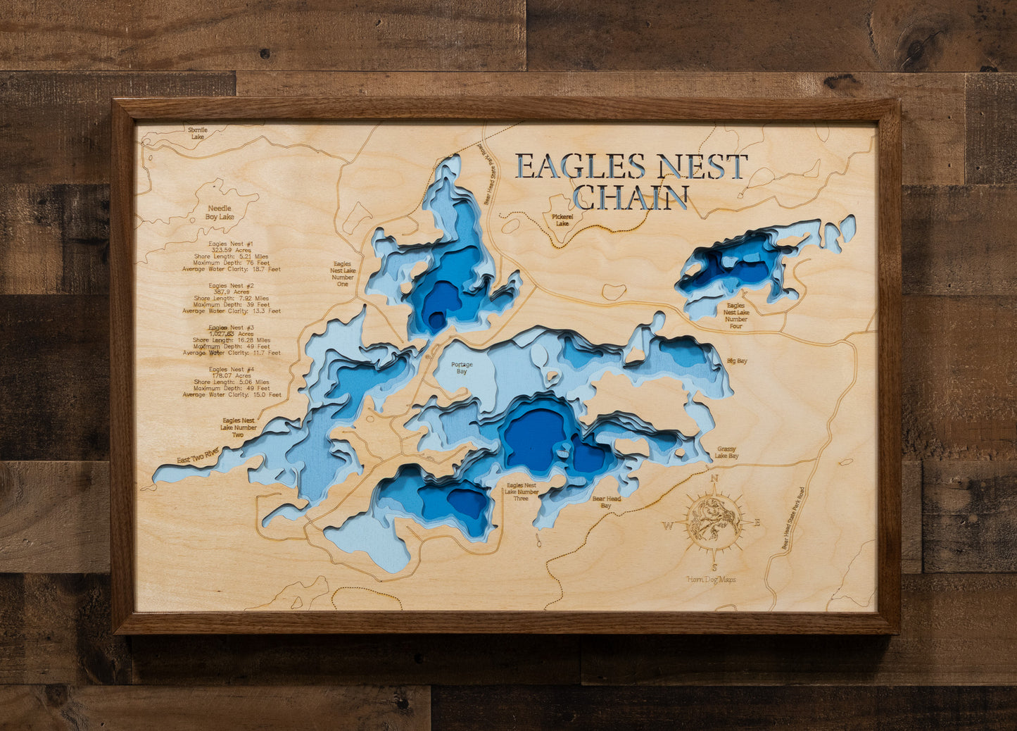 A laser-cut, layered wooden map of the Eagles Nest Chain of Lakes in St. Louis County, Minnesota. The distinct shapes of Eagles Nest Lakes #1, #2, and #3, and their interconnected channels, are clearly visible within the forested landscape of northeastern Minnesota. The varying depths of the lakes, reaching a maximum of 76 feet, are represented by different layers of wood, illustrating their impressive underwater topographies.