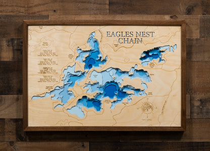 A laser-cut, layered wooden map of the Eagles Nest Chain of Lakes in St. Louis County, Minnesota. The distinct shapes of Eagles Nest Lakes #1, #2, and #3, and their interconnected channels, are clearly visible within the forested landscape of northeastern Minnesota. The varying depths of the lakes, reaching a maximum of 76 feet, are represented by different layers of wood, illustrating their impressive underwater topographies.