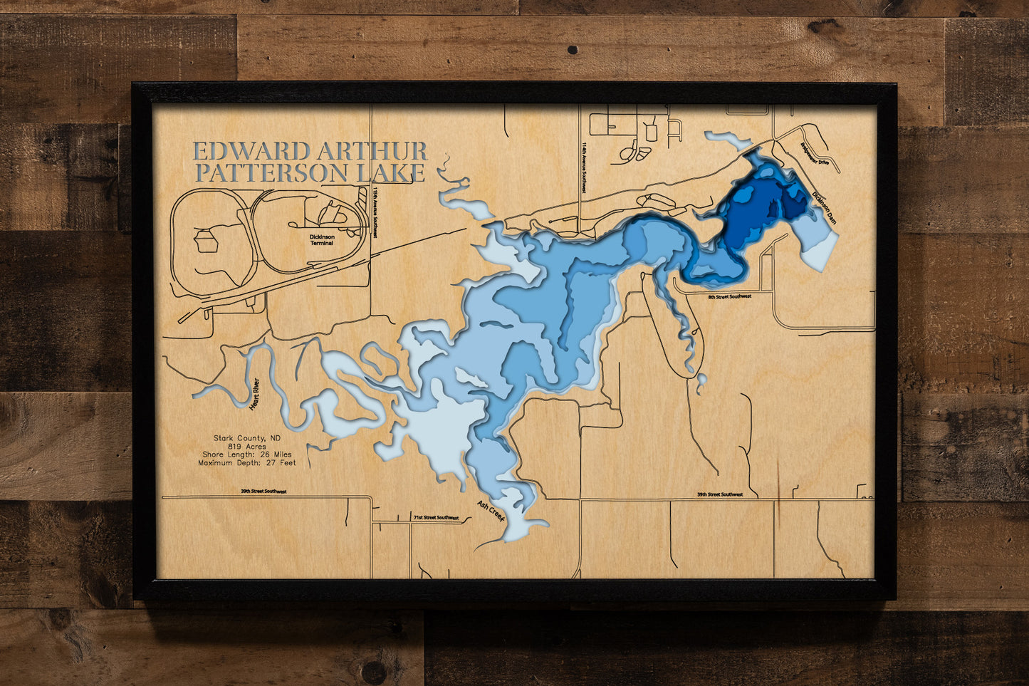 A precision laser-cut, multi-layered wooden map of Edward Arthur Patterson Lake in Stark County, North Dakota — a Heart River reservoir just west of Dickinson with 26 miles of prairie shoreline. The natural wood top layer captures the lake's winding shoreline in fine detail, while a light-to-dark blue gradient conveys its 27-foot depth. A handcrafted statement piece for any North Dakota lake home, Great Plains cabin, or outdoor enthusiast's wall.