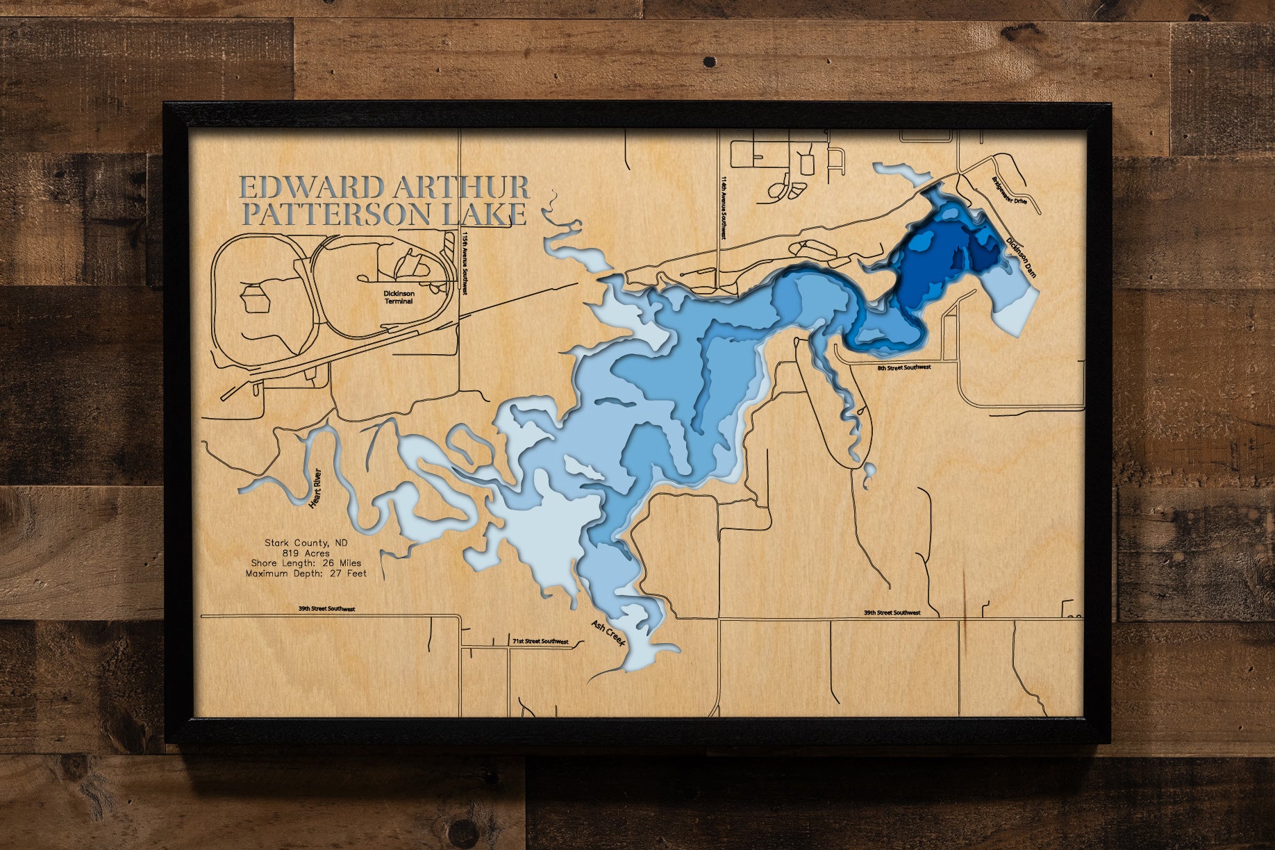 A precision laser-cut, multi-layered wooden map of Edward Arthur Patterson Lake in Stark County, North Dakota — a Heart River reservoir just west of Dickinson with 26 miles of prairie shoreline. The natural wood top layer captures the lake's winding shoreline in fine detail, while a light-to-dark blue gradient conveys its 27-foot depth. A handcrafted statement piece for any North Dakota lake home, Great Plains cabin, or outdoor enthusiast's wall.