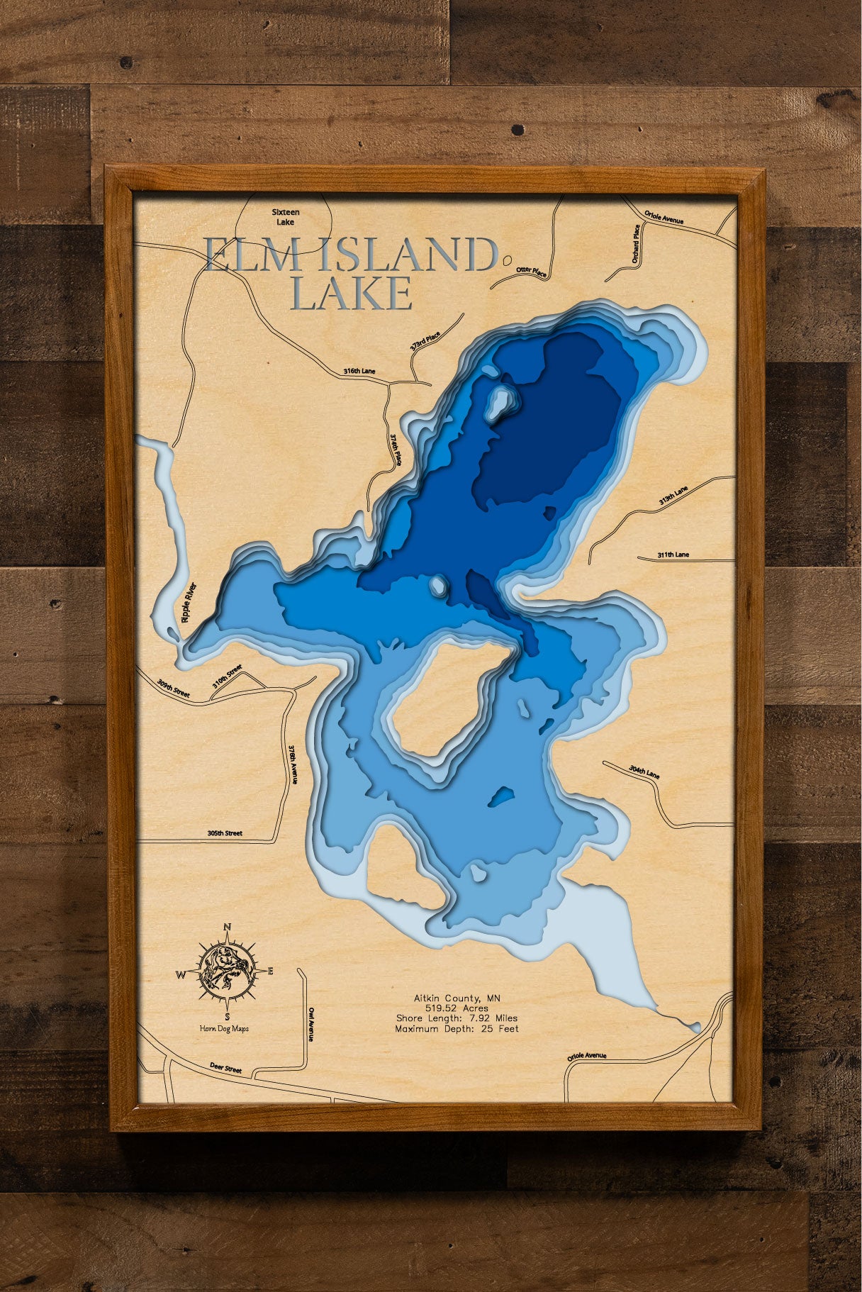  laser-cut, layered wooden map of Elm Island Lake in Aitkin County, Minnesota. The shape of the lake, with its 7.92-mile shoreline, is visible within the central Minnesota landscape. The varying depths of the lake, reaching a maximum of 25 feet, are represented by different layers of wood.
